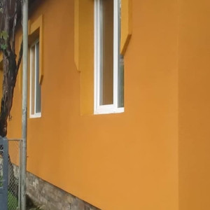 Стіна з вікнами приватного будинку, облицьована штукатуркою короїд фото